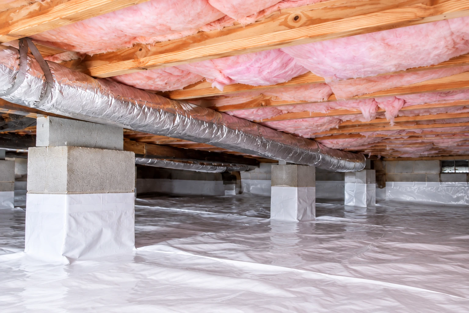 Crawl space with pink insulation between floor joists, a silver duct, concrete piers, and a white vapor barrier covering the ground.
